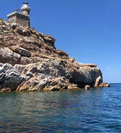 Il faro dello Scoglietto sull'isola rocciosa circondata dal mare cristallino all'Isola d'Elba