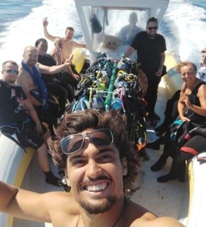 Team istruttori e gruppo subacquei sorridenti su un gommone del Baratti Diving, pronti per un'immersione allo Scoglietto dell'Isola d'Elba